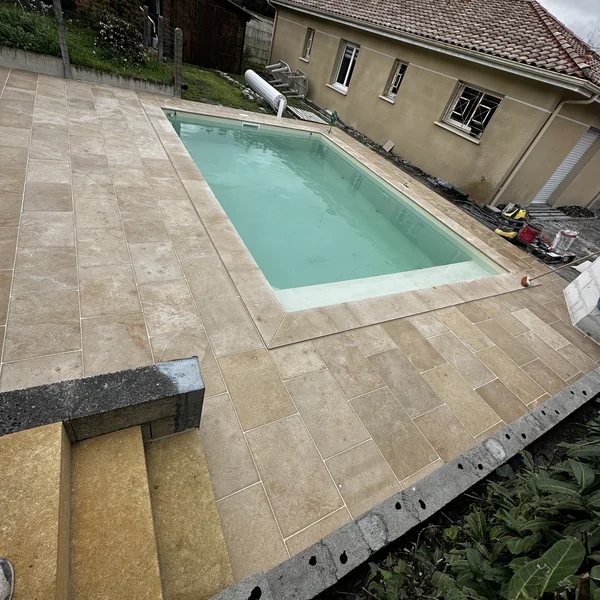 Plage de piscine carrelée en travertin avec margelles