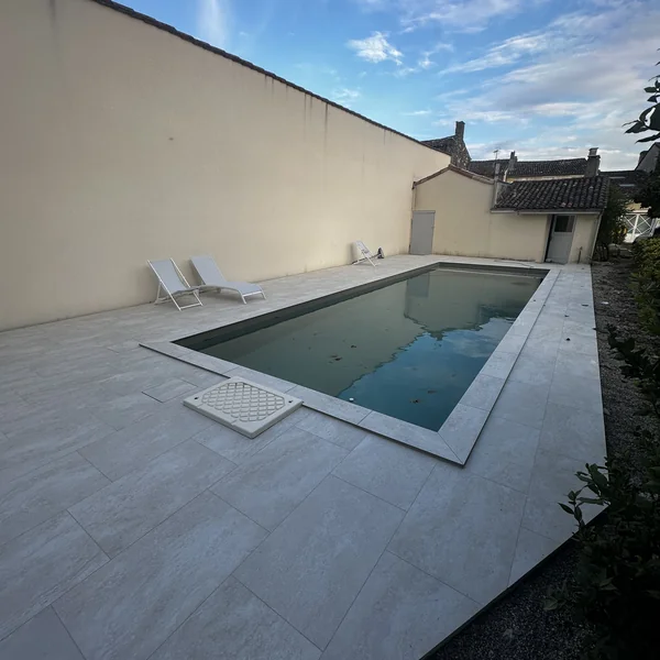 Plage de piscine en carrelage effet pierre claire