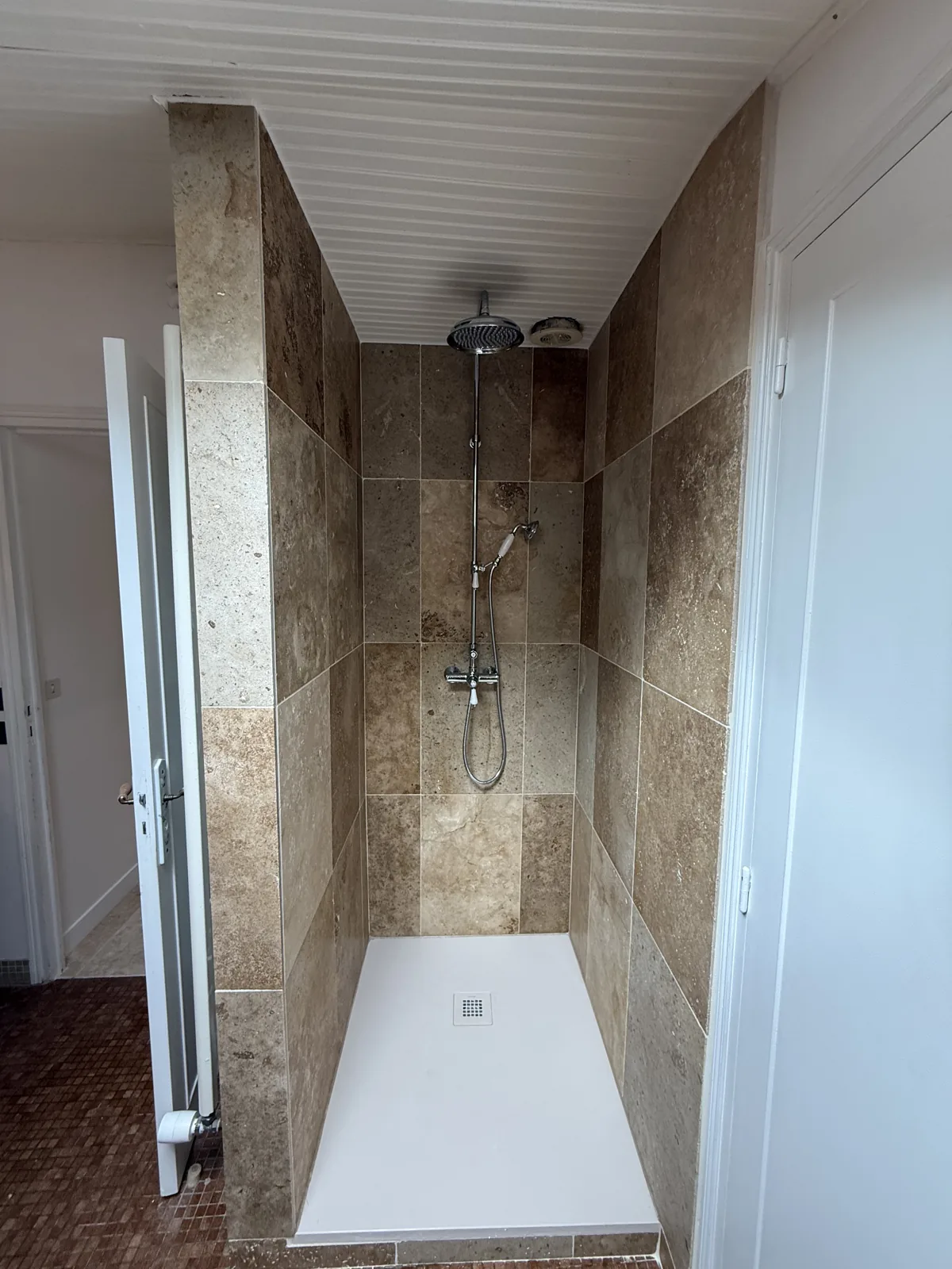 Douche à l'italienne carrelée en travertin avec colonne de douche chromée